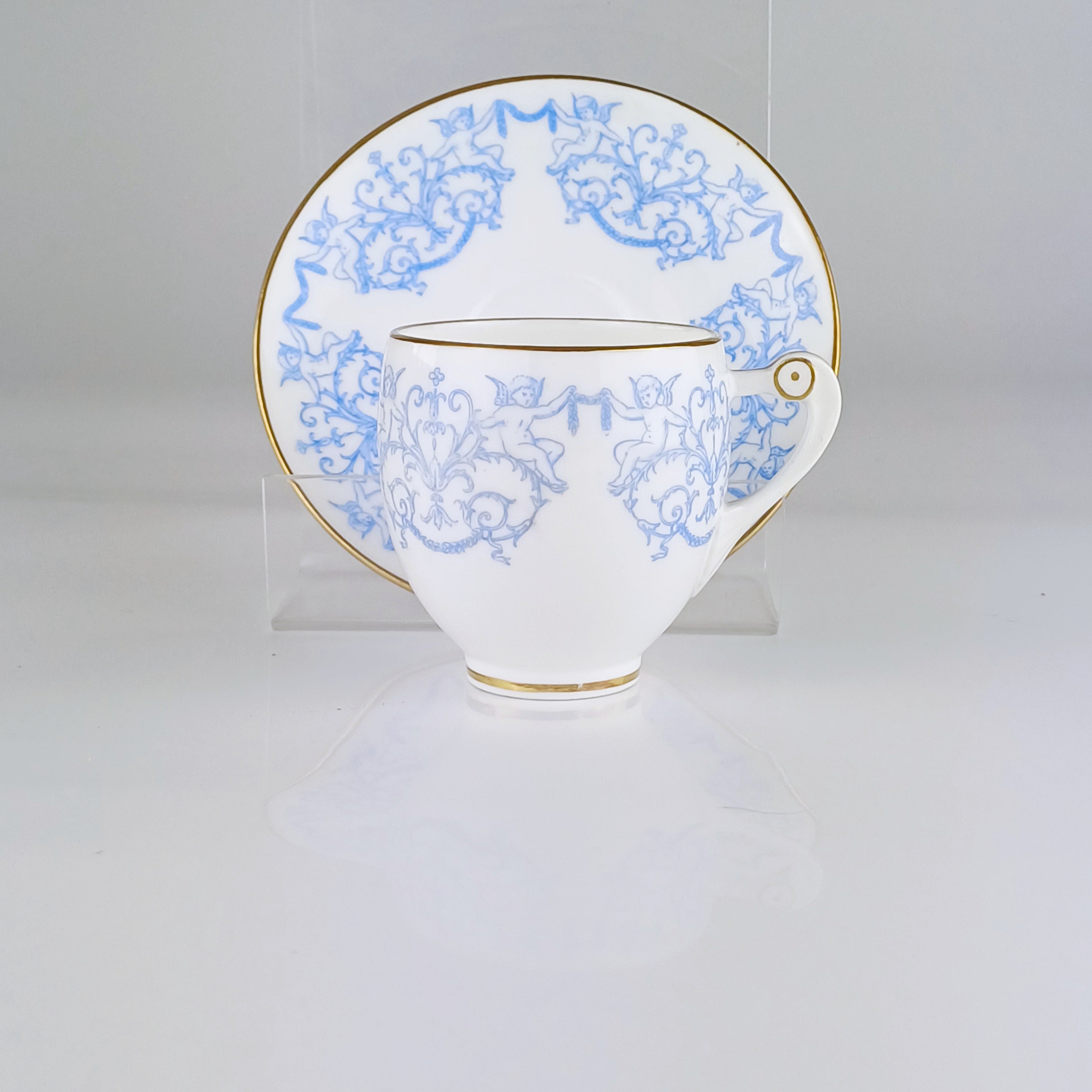 White teacup and saucer with blue floral patterns on a white background