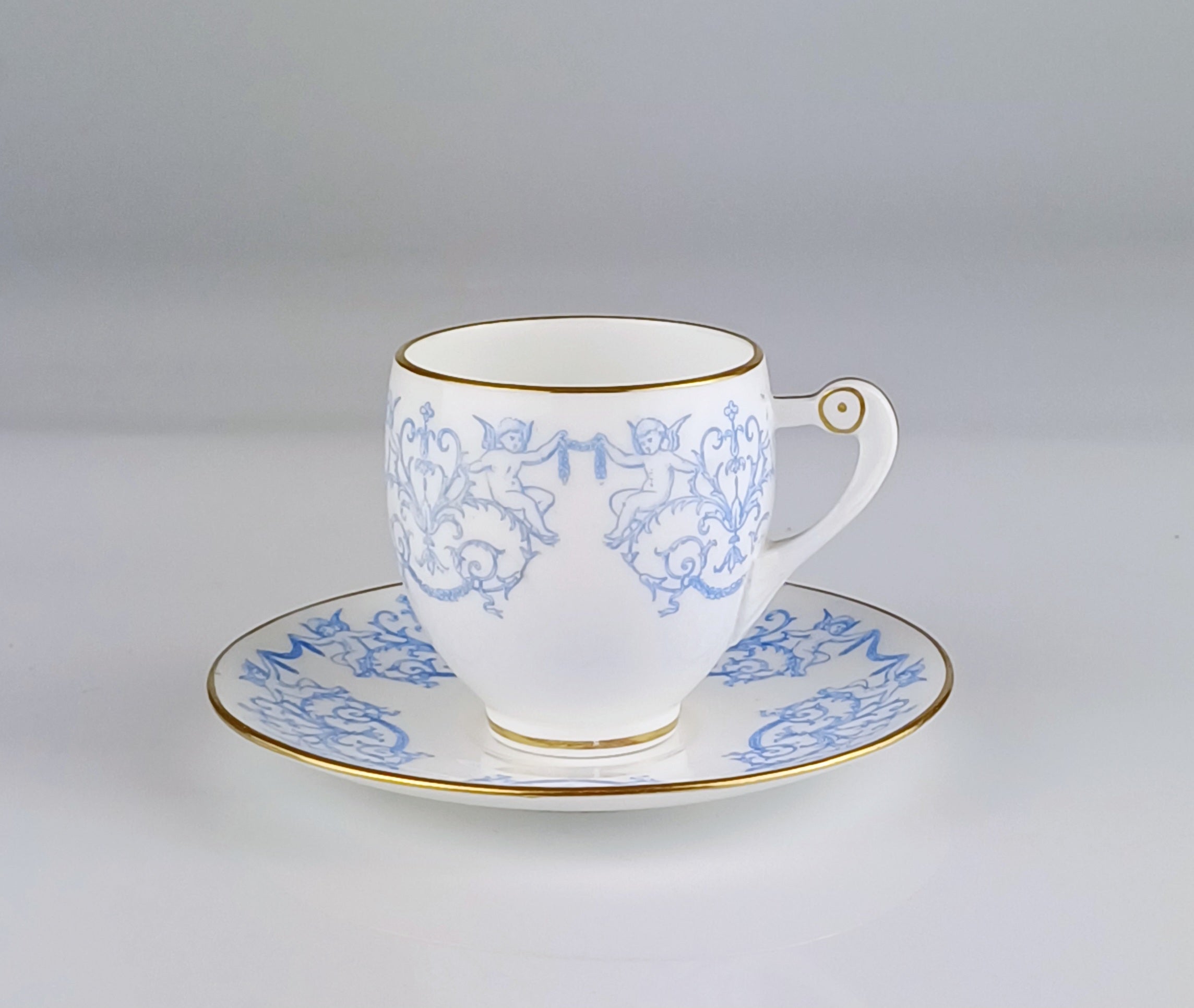 White teacup and saucer with blue floral patterns on a gray background